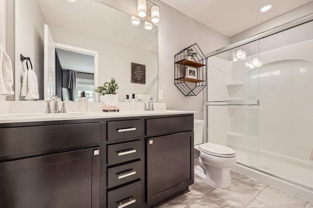 bathroom featuring toilet, a shower with shower door, and vanity