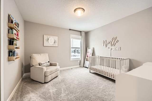 carpeted bedroom featuring a textured ceiling and a crib