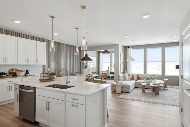 kitchen with white cabinets, dishwasher, and a center island with sink