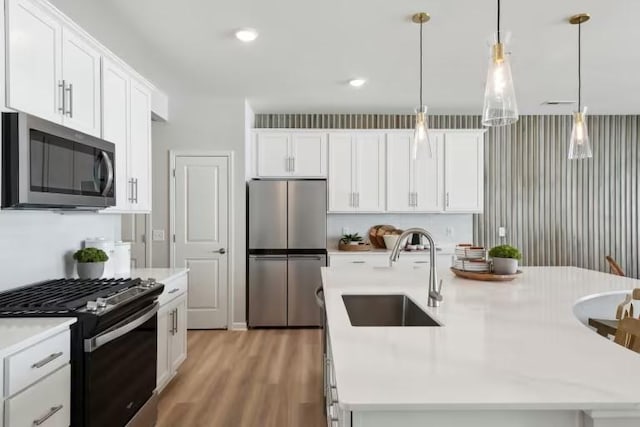 kitchen featuring white cabinetry, sink, stainless steel appliances, and a center island with sink