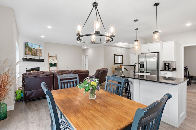 dining area featuring a notable chandelier, a fireplace, and light wood-type flooring