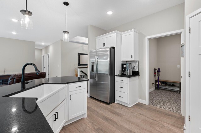 kitchen with stainless steel refrigerator with ice dispenser, sink, pendant lighting, and white cabinets