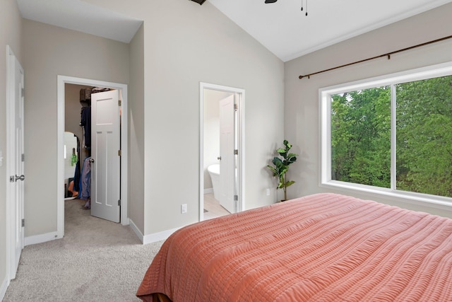 bedroom featuring lofted ceiling, ceiling fan, ensuite bathroom, light carpet, and a walk in closet