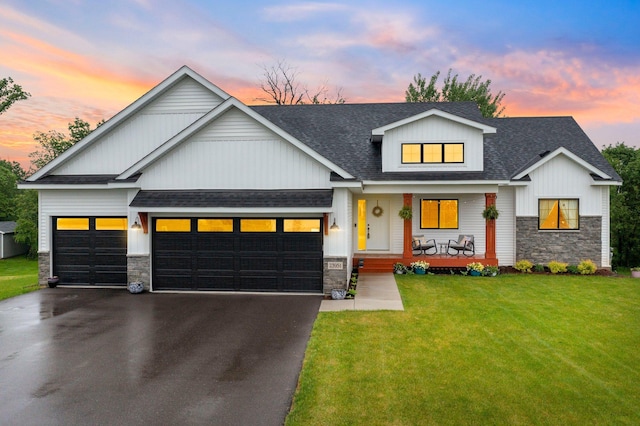 view of front of house with a garage, covered porch, and a lawn