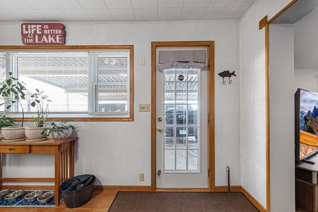 doorway featuring crown molding and baseboards