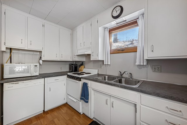 kitchen featuring under cabinet range hood, dark countertops, a sink, white appliances, and white cabinetry
