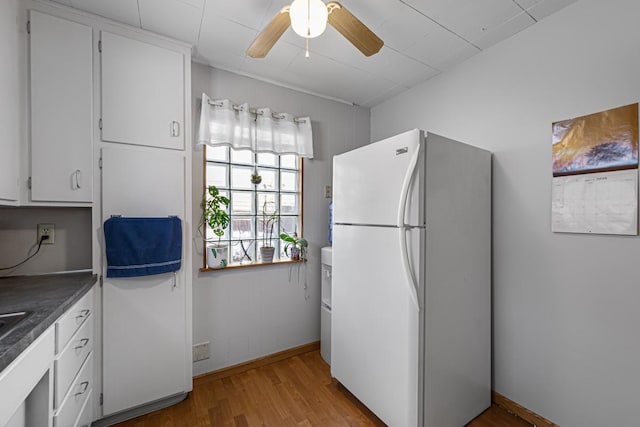 kitchen featuring a ceiling fan, dark countertops, light wood-style flooring, white cabinets, and freestanding refrigerator
