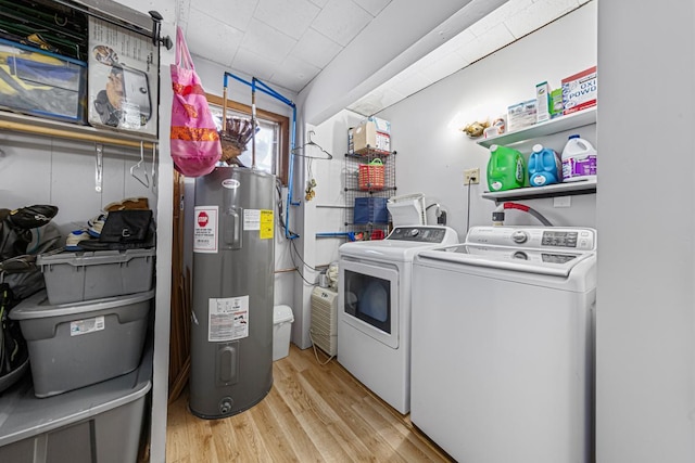 clothes washing area featuring light wood-style flooring, washing machine and clothes dryer, laundry area, and electric water heater