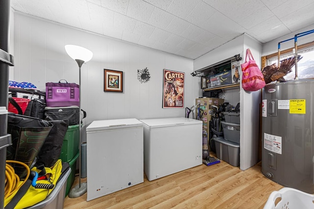 clothes washing area featuring water heater, light wood-style floors, washer and dryer, and laundry area