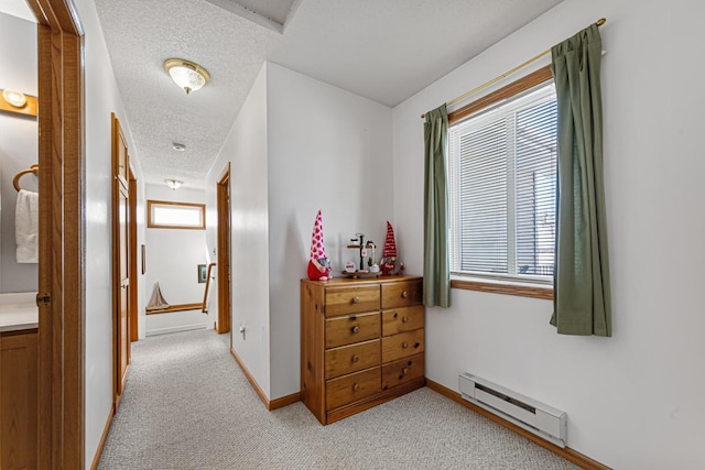 corridor featuring a baseboard radiator, light carpet, a textured ceiling, and baseboards