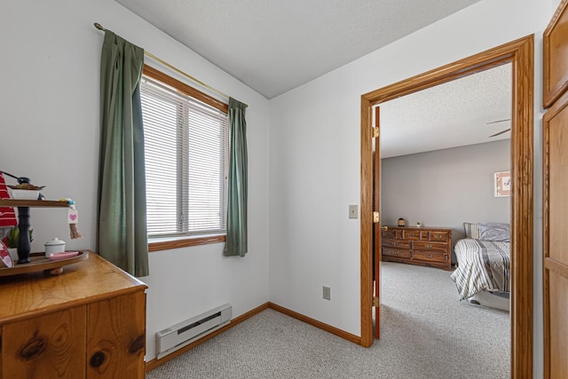 interior space with a baseboard heating unit, baseboards, a textured ceiling, and light colored carpet