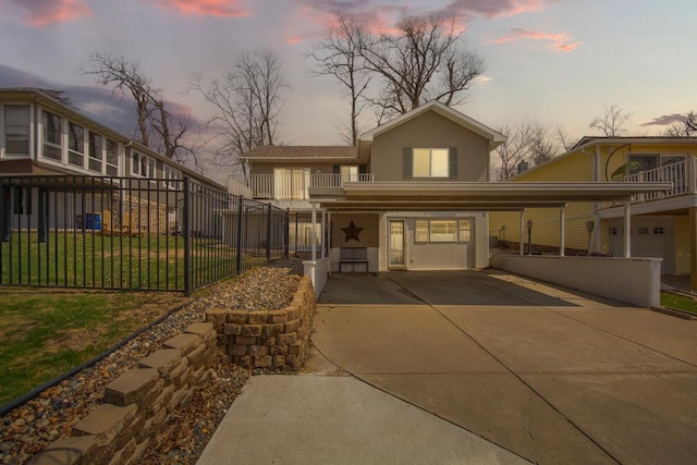 view of front facade featuring fence, a balcony, concrete driveway, a carport, and a front yard