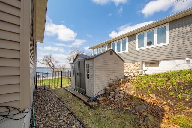 exterior space featuring fence, an outbuilding, a storage shed, and a water view