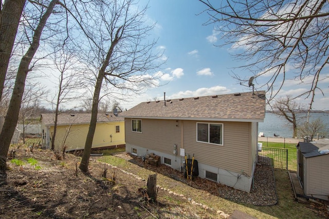 back of house featuring roof with shingles and fence