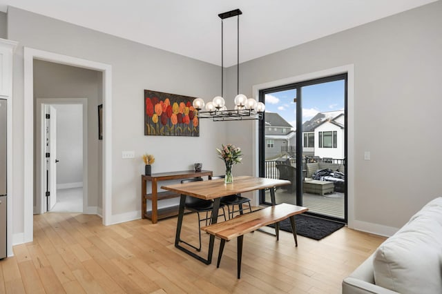 dining room with light hardwood / wood-style flooring and an inviting chandelier