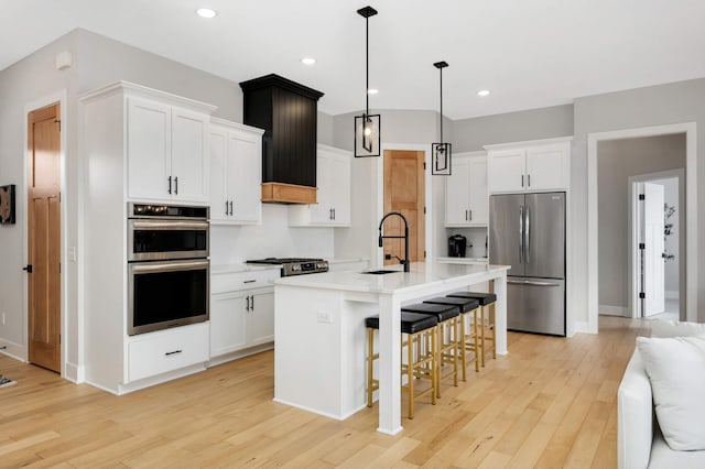 kitchen featuring sink, an island with sink, white cabinets, and appliances with stainless steel finishes