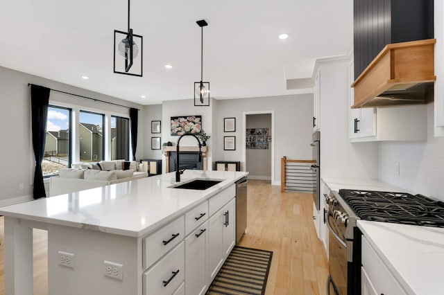 kitchen featuring sink, white cabinets, stainless steel appliances, and an island with sink