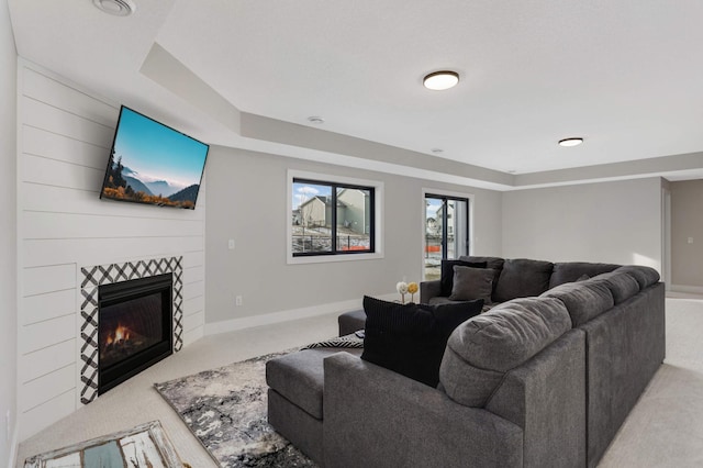 living room featuring carpet floors, a large fireplace, and a raised ceiling