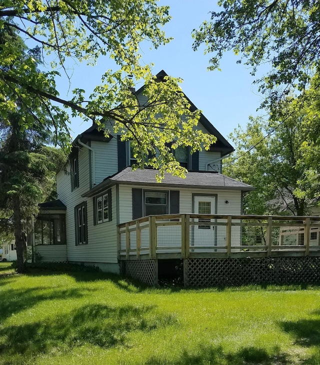 rear view of house featuring a deck and a lawn