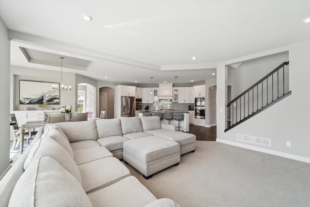 living room featuring a tray ceiling and a chandelier