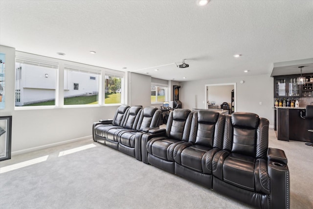 carpeted cinema room featuring bar area and a textured ceiling