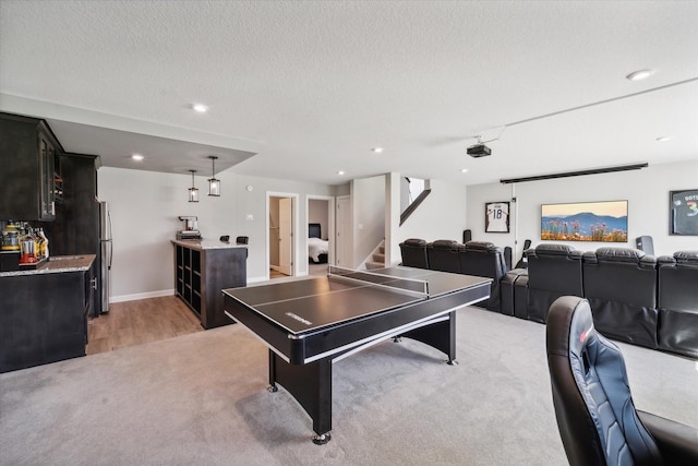 rec room featuring light colored carpet, bar area, and a textured ceiling