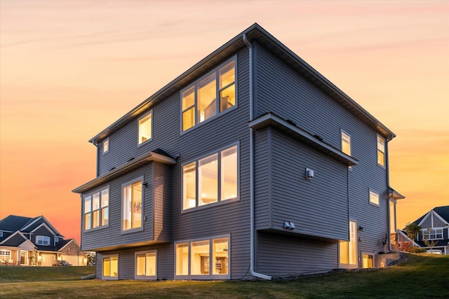 back house at dusk with a lawn