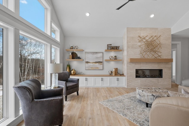 living room with light hardwood / wood-style floors, ceiling fan, and a tiled fireplace