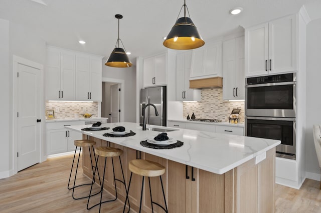 kitchen featuring sink, white cabinetry, and a kitchen island with sink