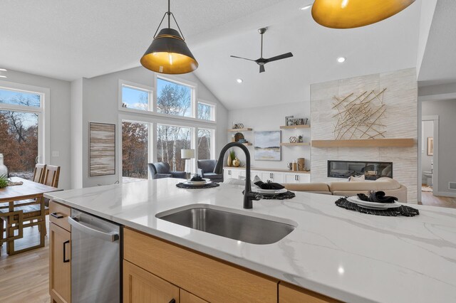 kitchen featuring sink, dishwasher, pendant lighting, and light stone countertops