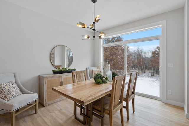 dining space featuring light wood-type flooring and a notable chandelier