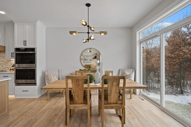 dining room with light hardwood / wood-style floors and an inviting chandelier