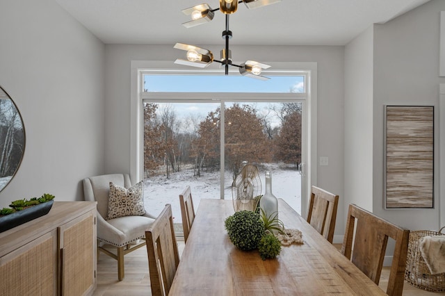 dining room featuring a healthy amount of sunlight, light wood-type flooring, and an inviting chandelier