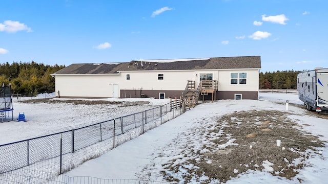 snow covered rear of property featuring a trampoline