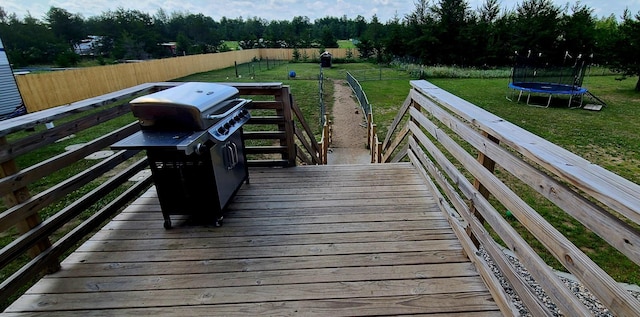 deck featuring area for grilling, a trampoline, and a lawn