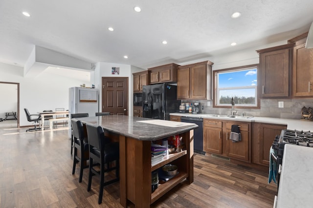 kitchen with tasteful backsplash, a center island, dark hardwood / wood-style flooring, and black appliances