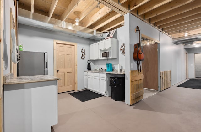 15743 County Road 31, Menahga, MN 56464 - kitchen featuring freestanding refrigerator, light countertops, white cabinets, and concrete flooring