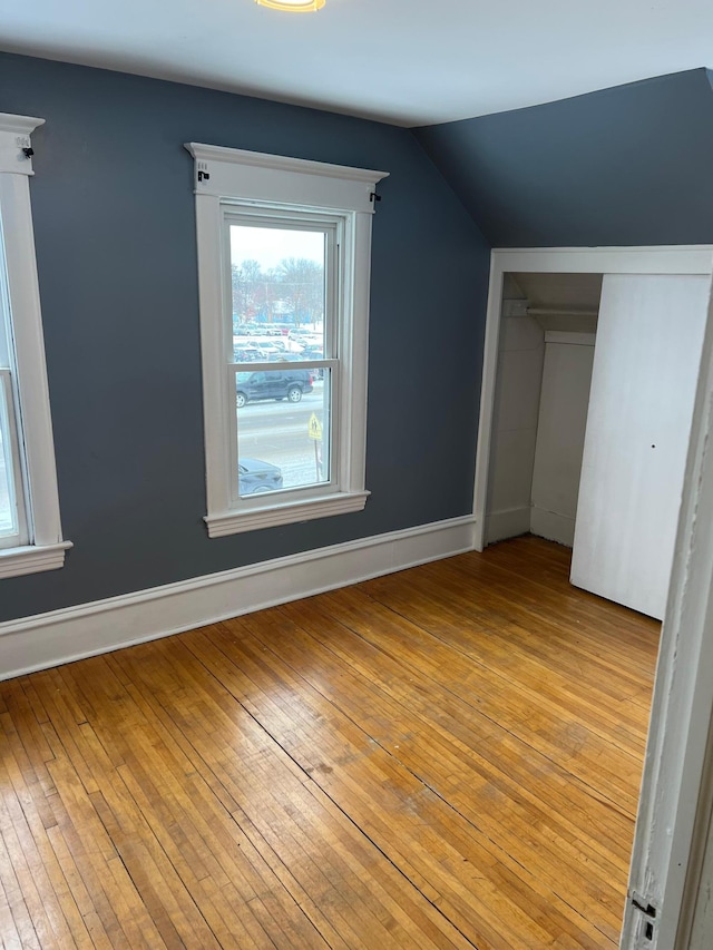 additional living space featuring light wood-type flooring and vaulted ceiling