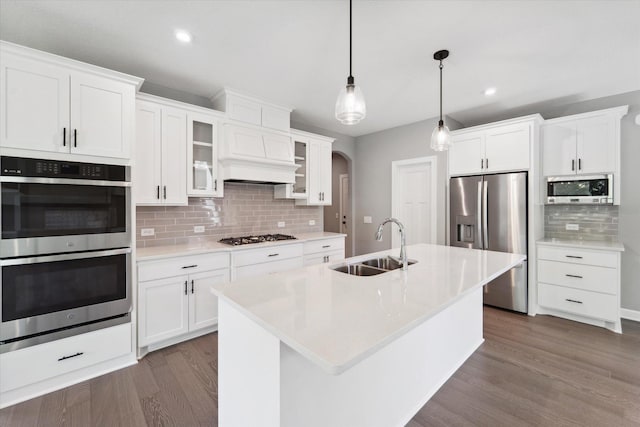 kitchen featuring appliances with stainless steel finishes, white cabinetry, decorative light fixtures, and sink