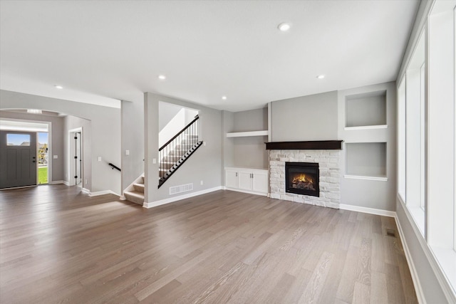 unfurnished living room featuring hardwood / wood-style floors, built in features, and a fireplace