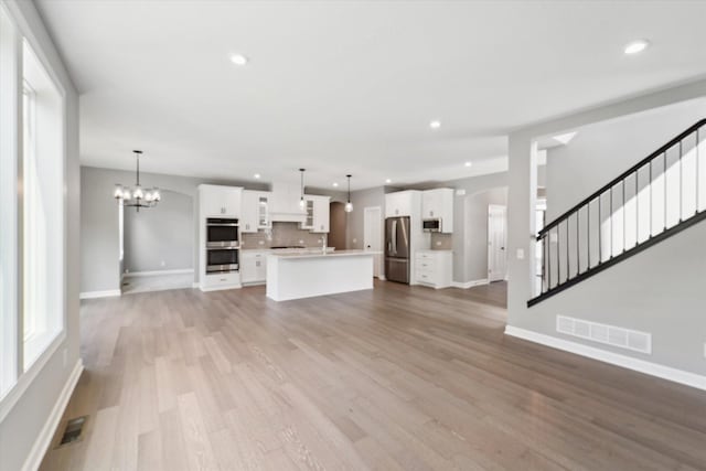 unfurnished living room featuring wood-type flooring and a notable chandelier