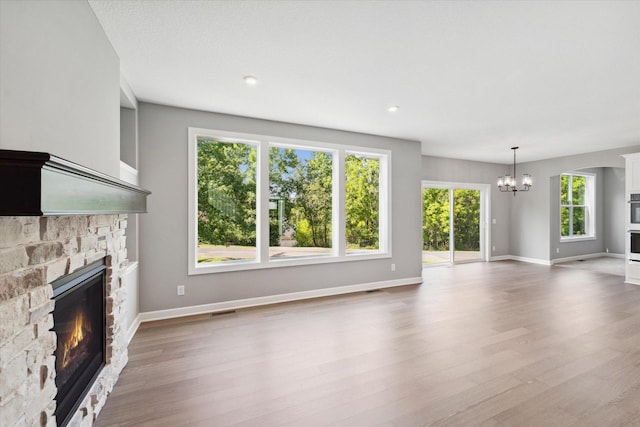 unfurnished living room with a fireplace, a chandelier, and hardwood / wood-style flooring