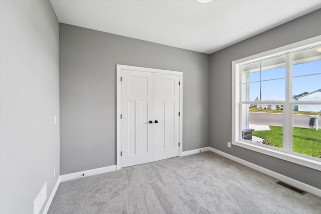 unfurnished bedroom with light colored carpet and a closet