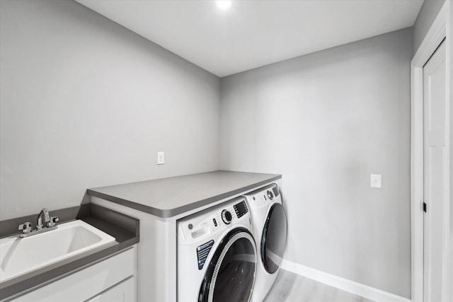 clothes washing area featuring sink, separate washer and dryer, and light hardwood / wood-style flooring