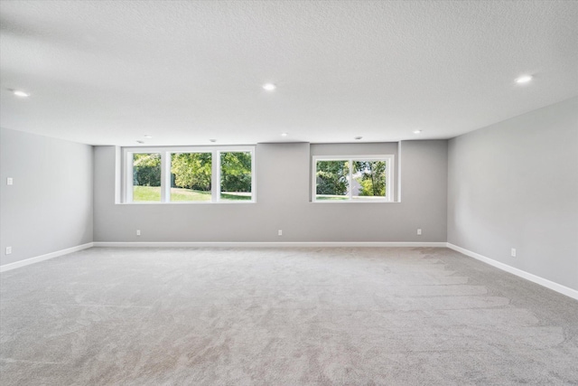 carpeted spare room with plenty of natural light and a textured ceiling