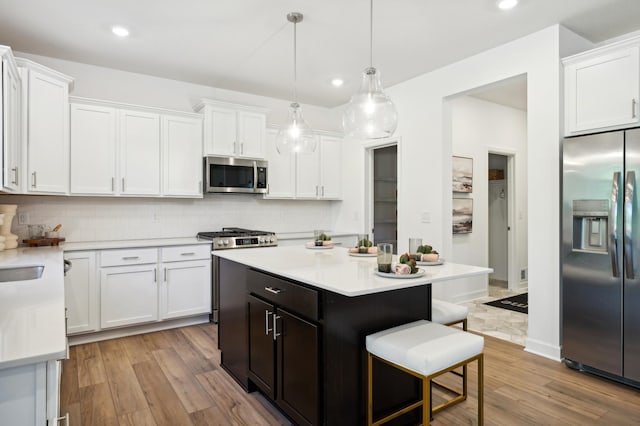 kitchen with tasteful backsplash, white cabinets, appliances with stainless steel finishes, and a kitchen island