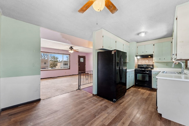 kitchen featuring sink, black appliances, a textured ceiling, hardwood / wood-style floors, and backsplash