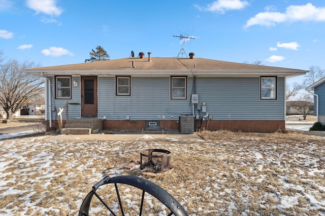 snow covered back of property featuring central AC