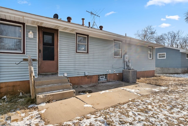 snow covered rear of property featuring cooling unit and a patio