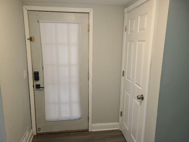 doorway featuring dark wood-style floors and baseboards